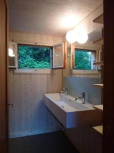 ein Badezimmer mit einem großen Waschbecken und zwei Fenstern in der Unterkunft Studeweidli 6-Bettwohnung in Hasliberg