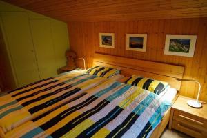 um quarto com uma cama com um edredão listrado em 4-Bett- Ferienwohnung Brachli em Innertkirchen