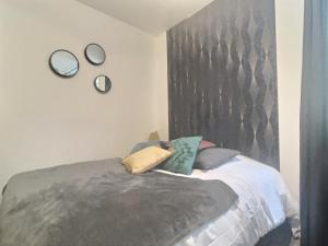 a bedroom with a bed with a gray headboard and pillows at Le Foch in Chalons en Champagne