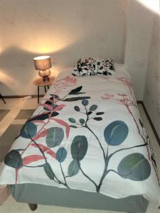 a bed with a blanket on it with a lamp at Best possible location, 1 bedroom apartment in Närpiö