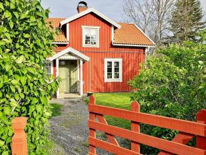 una casa roja con una valla delante en Holiday home GRISSLEHAMN VIII en Grisslehamn