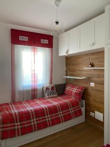 a bedroom with a bed with a red plaid blanket at Appartamento Antey Saint André posizione centrale in Antey-Saint-André