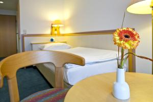 ein Hotelzimmer mit einer Vase mit einer Blume auf dem Tisch in der Unterkunft Leine-Hotel in Göttingen