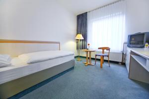a hotel room with a bed and a table and a television at Leine-Hotel in Göttingen
