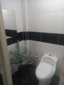 a bathroom with a toilet and a glass sink at Hotel Avei Suites in Cali