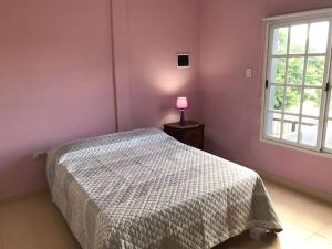 ein Schlafzimmer mit einem Bett und einer rosa Wand in der Unterkunft Maximo confort en Salta in Salta