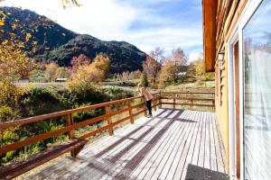 a person standing on a wooden deck on a house at Chile Wild - Las Vertientes in Malalcahuello