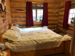 um quarto com uma cama num chalé de madeira em Beaver Guest Ranch em Bridge Lake