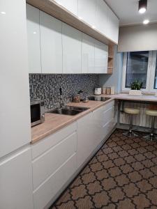 a kitchen with white cabinets and a sink at Apartament Grunwaldzka in Przemyśl