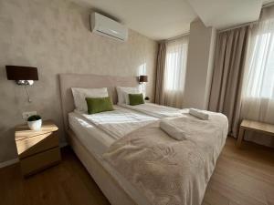 a bedroom with a large white bed with green pillows at University city life bestern in Szeged