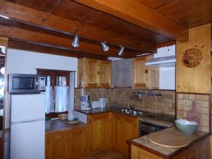 eine Küche mit Holzschränken und einem weißen Kühlschrank in der Unterkunft Chalet Pralognan-la-Vanoise, 3 pièces, 6 personnes - FR-1-464-16 in Pralognan-la-Vanoise