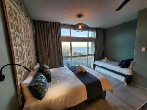 a bedroom with two beds and a large window at Escape to 203 Umdloti Holiday Resort in Umdloti