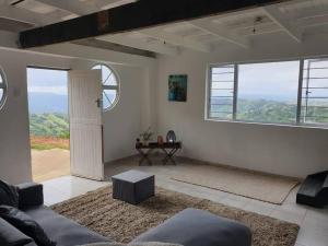 a living room with a couch and some windows at Best view of 1000 Hills with shared pool. in Bothaʼs Hill