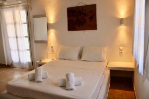 a bedroom with a white bed with two towels on it at Iliovasilema Studios Koufonisi in Koufonisia