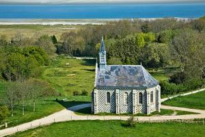 eine alte Kirche auf einem Feld mit dem Meer im Hintergrund in der Unterkunft Le bon coin en Baie de Somme in Boismont