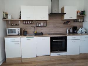 cocina con armarios blancos y microondas en Relax Appartement, en Bad Radkersburg