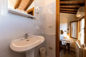 a white bathroom with a sink and a mirror at [Centro Storico - 5 Stelle] Chalet con Suite in San Gimignano