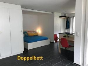 a bedroom with a bed and a table and a kitchen at Studio Ruben 2-Bett Wohnung in Meiringen
