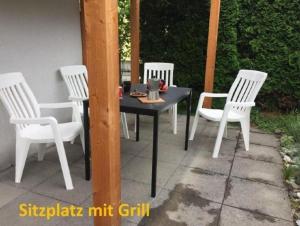 four white chairs and a table on a patio at Studio Ruben 2-Bett Wohnung in Meiringen
