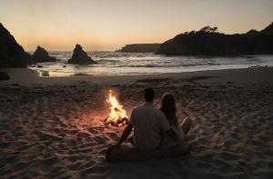 ein Paar, das neben einem Lagerfeuer am Strand sitzt in der Unterkunft SCP Mendocino Inn and Farm in Little River