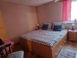 Un dormitorio con una cama con almohadas azules y una ventana en Penzión U Koníka, en Liptovský Ján