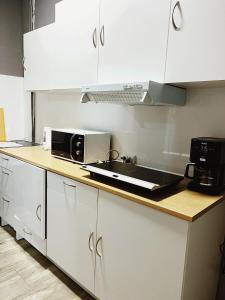 eine Küche mit weißen Schränken, einer Spüle und einer Mikrowelle in der Unterkunft Rio Hostel in Madrid