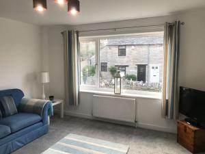 a living room with a blue couch and a window at Church View - 2 bed Cosy Cottage in Swanage in Swanage