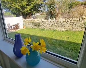 dos jarrones azules sentados en el alféizar de una ventana con flores en Church View - 2 bed Cosy Cottage in Swanage, en Swanage