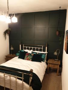 a bedroom with a large bed with green walls at Dora Cottage in Formby