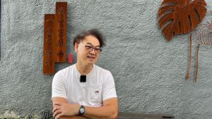 un homme assis à une table devant un bâtiment dans l'établissement 輕塵別院Serenegray B&B, à Wujie