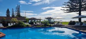 una gran piscina con sillas y sombrillas en Private Suite Nautilus Beach Front Resort en Coffs Harbour