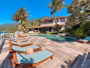 a house with a swimming pool with lounge chairs at Vilatoro Guest House in Ilhabela