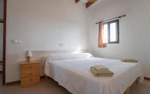 a white bedroom with a white bed and a window at APARTAMENTOS CASA EUGENIO FORMENTERA in La Savina