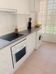 Biała kuchnia z pralką i zmywarką do naczyń w obiekcie Apartamento a 2 min de playa w mieście Calpe