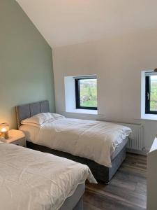 1 dormitorio con 2 camas y 2 ventanas en Cheerful 3 bedroom cottage with great seaview, en Drogheda