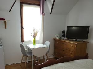 a bedroom with a tv and a table and a tv stand at rêvedelac meublé tout confort in Brêmes