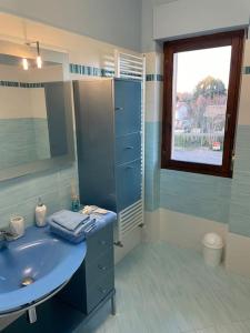 ein Badezimmer mit einem blauen Waschbecken und einem Fenster in der Unterkunft Civita Home in Bagnoregio