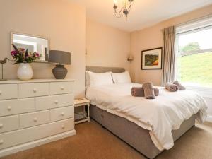 a bedroom with a bed and a dresser and a window at Dales Cottage in Grassington