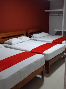 two beds with red and white sheets in a room at Hotel MCH in Veracruz