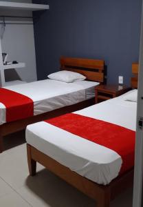 two beds with red and white sheets in a room at Hotel MCH in Veracruz