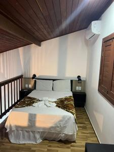 a bedroom with a large bed with white sheets at Pousada Pipa Imperial in Pipa