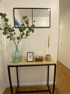 einen Tisch mit einer Vase und einer Pflanze darauf in der Unterkunft Superbe appartement proche de Paris in Colombes