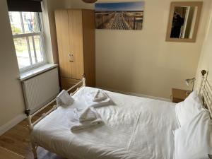 a white bed in a room with a window at Jolly Roger Cottage - Part of the The Bay Filey Holiday Village with pool, gym and direct beach access, pub, restaurant, tennis and meadows walks in Filey +33 photos