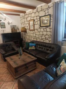 a living room with leather furniture and a stone wall at Siedlisko Lubicz Stara Chata Kazimierz Dolny in Kazimierz Dolny