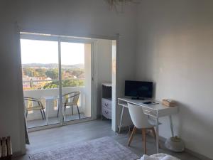 a room with a desk with a computer and a balcony at Hôtel Paradis in Bormes-les-Mimosas