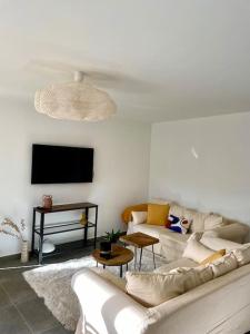 ein Wohnzimmer mit einem weißen Sofa und einem TV in der Unterkunft Vue panoramique - résidence calme - St Raphaël in Saint-Raphaël