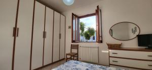 a bedroom with a mirror and a dresser and a window at Amici di Calabria in Scalea