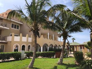 two palm trees in front of a building at Tropical Morabeza Apartment Santa Maria in Santa Maria