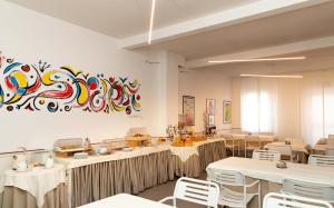 un restaurant avec des tables et des chaises et une peinture murale. dans l'établissement Hotel Solarium, à Civitanova Marche