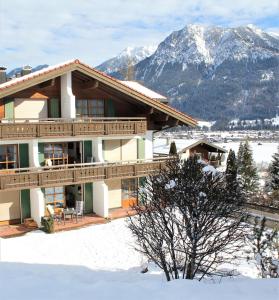 a house in the snow with mountains in the background at Ferienwohnung Bergflora in Oberstdorf